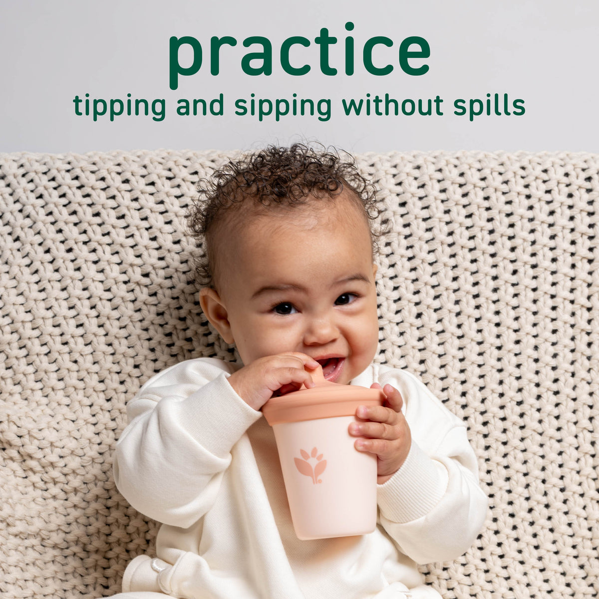Baby practicing tipping and sipping from a spill-resistant sippy cup