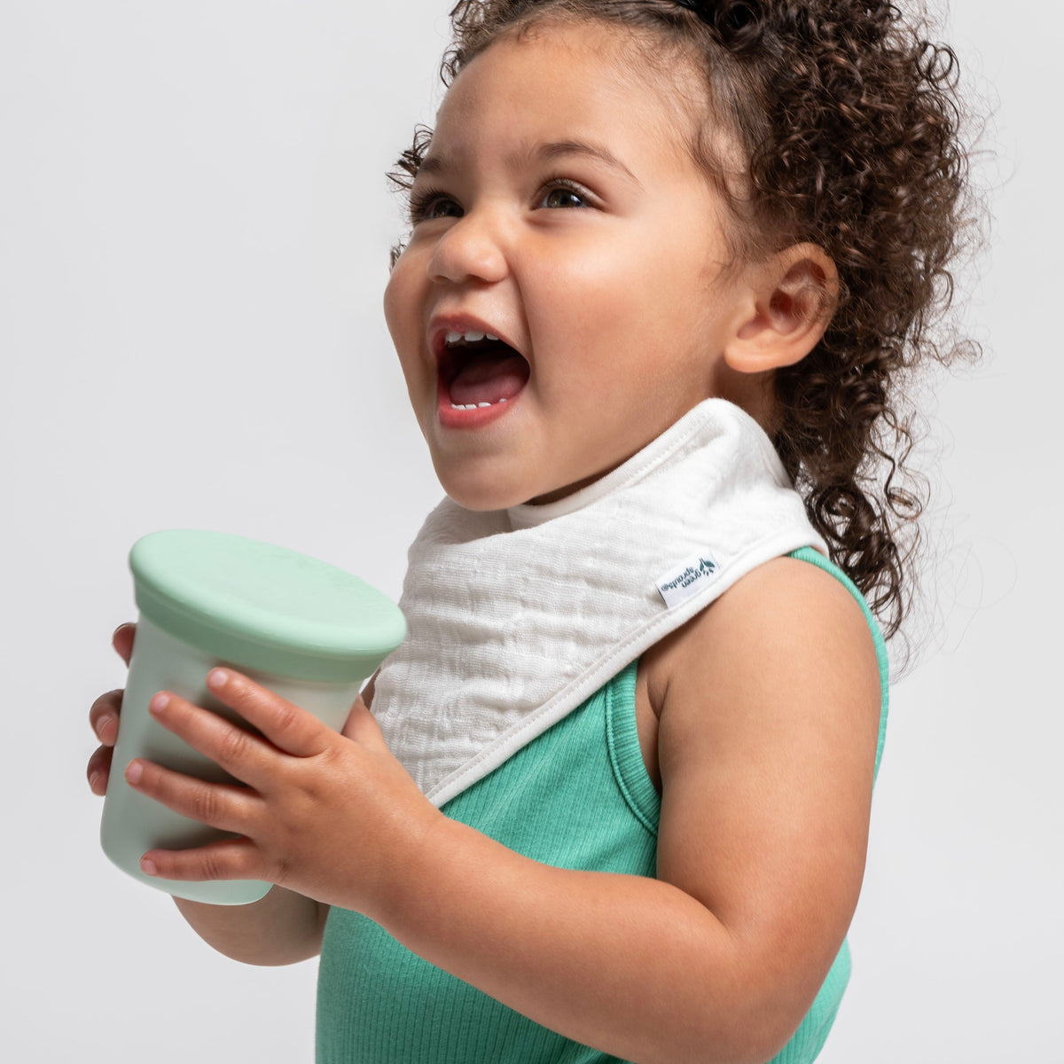 baby holding green sprouts 360 training cup and laughing