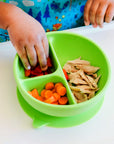 Little hands reaching into the green Learning Bowl made from Silicone