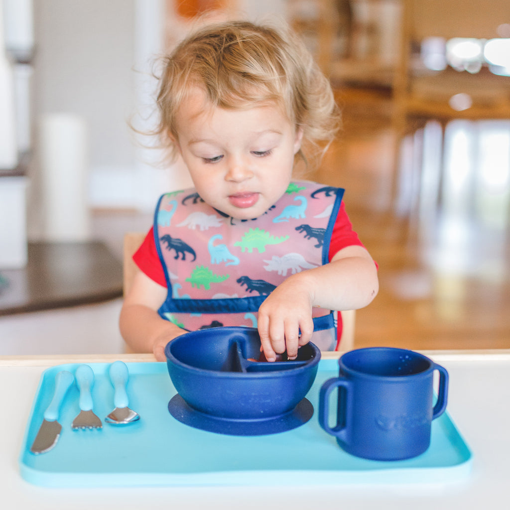 A two year-old boy reaching into the navy Learning Bowl made from Silicone