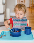 A young boy using the learning fork to get food from the navy Learning Bowl made from Silicone