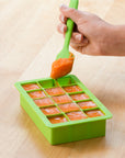 A beautiful carrot puree being put into the green Fresh Baby Food Freezer Tray.