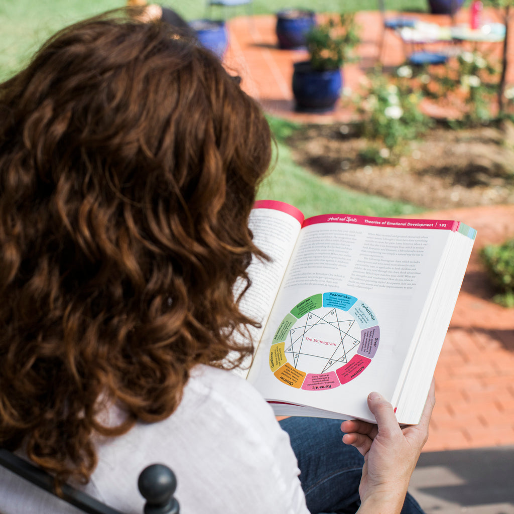 A woman reading the Grow Healthy. Grow Happy. The Whole Baby Guide in her backyard.
