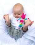 Baby playing with his feet in the air while holding the rabbit friend rattle.