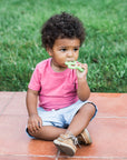 Little boy sitting outside while gnawing on the Front and Side Teether made from Silicone.