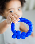 A little boy holding up to show off the blue blueberry Fruit Teether made from Silicone
