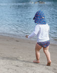Young boy running across the sand with a white Long Sleeve Rashguard Shirt