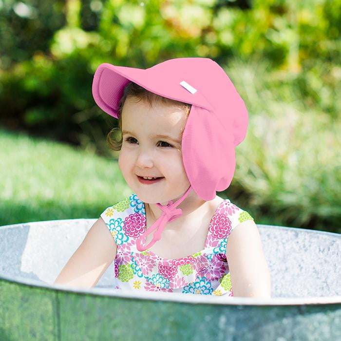 A smiling little girl wearing a pink Breathable Swim and Sun Flap Hat h in a galvanized oval tub in the backyard.