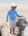 Young boy with a Light Blue Long Sleeve Rashguard Shirt inspecting the rocks on the beach